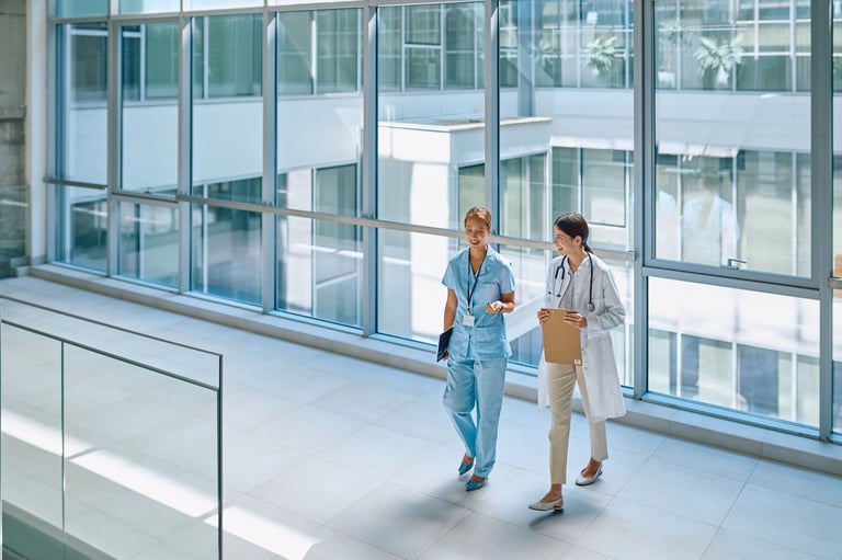 Doctor and nurse discussing patient diagnosis while walking through a modern, bright hospital corridor, collaborating on care and treatment